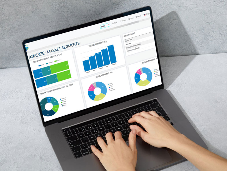 Hands typing on a laptop displaying a market segments analysis dashboard with colourful charts and graphs.